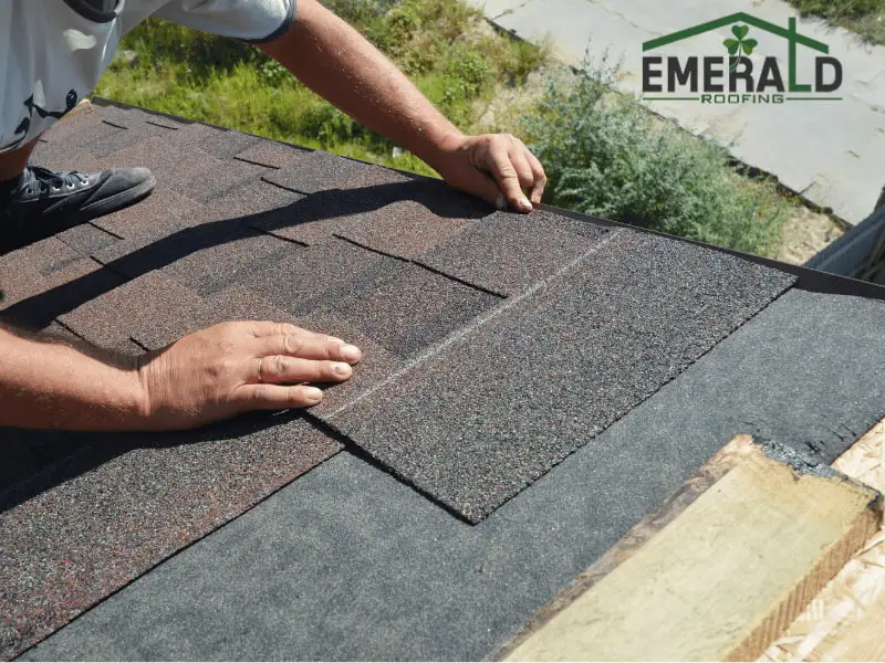 Roofing contractor installing asphalt shingles on a residential roof during storm damage roof repair